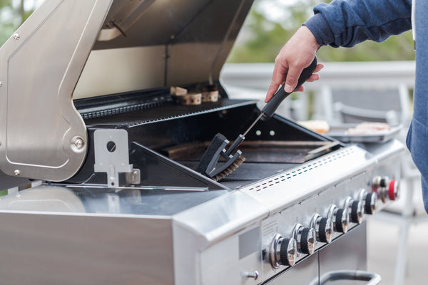 man cleaning grill with grill brush